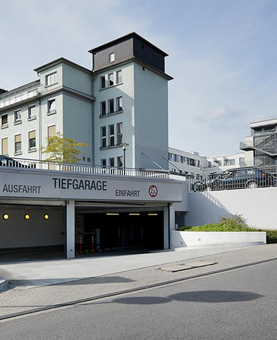 Blick zur Einfahrt der Tiefgarage des EVK Mettmann – im Hintergrund sieht man das Krankenhausgelände mit Neu- und Altbau.