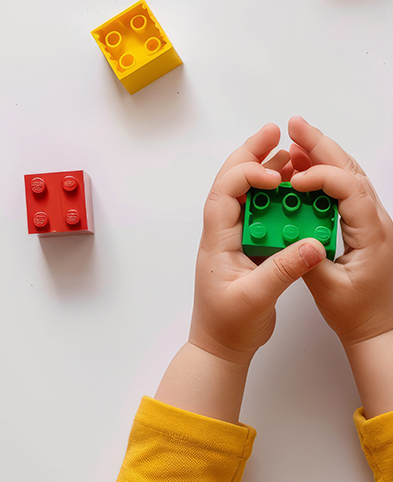 Kind mit bunten Spielbausteinen in der Hand.