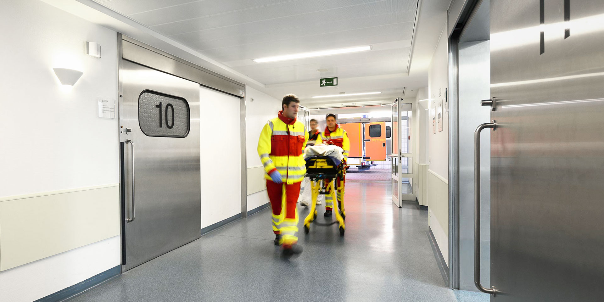 Zwei Sanitäter und ein Notarzt bringen einen Patienten auf einer Liege in einen Schockraum der Notaufnahme im EVK Mettmann.